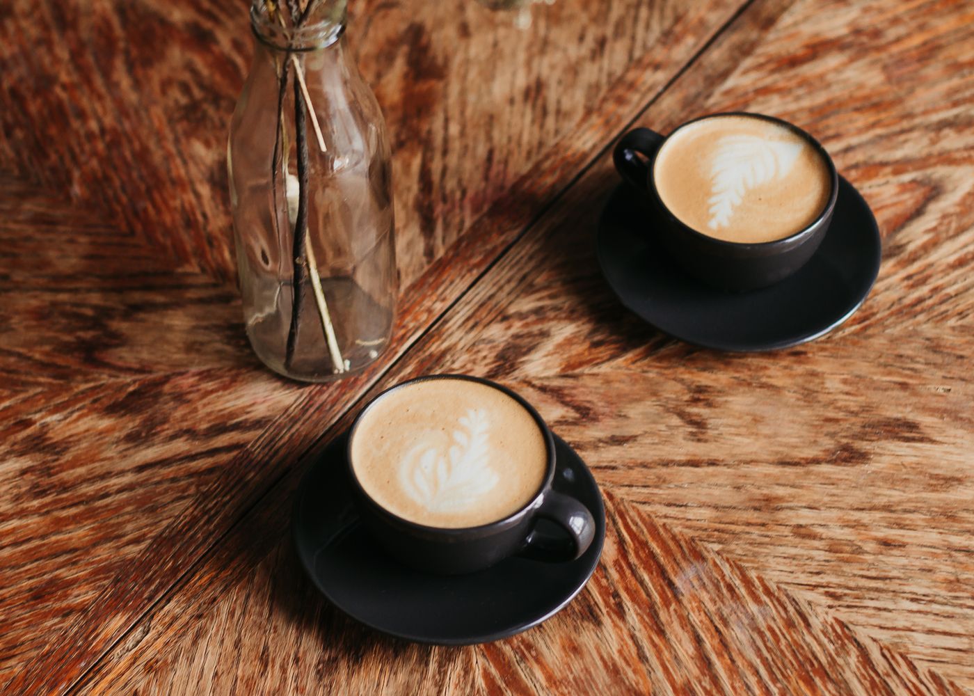 Two cups of coffee on a warm wooden table, set for a conversation