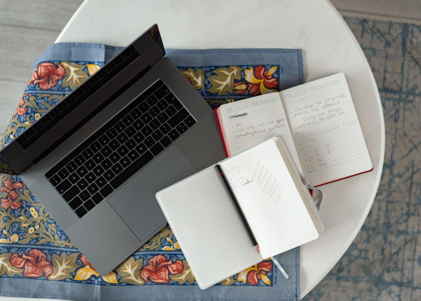 A laptop and handwritten notebooks on a table