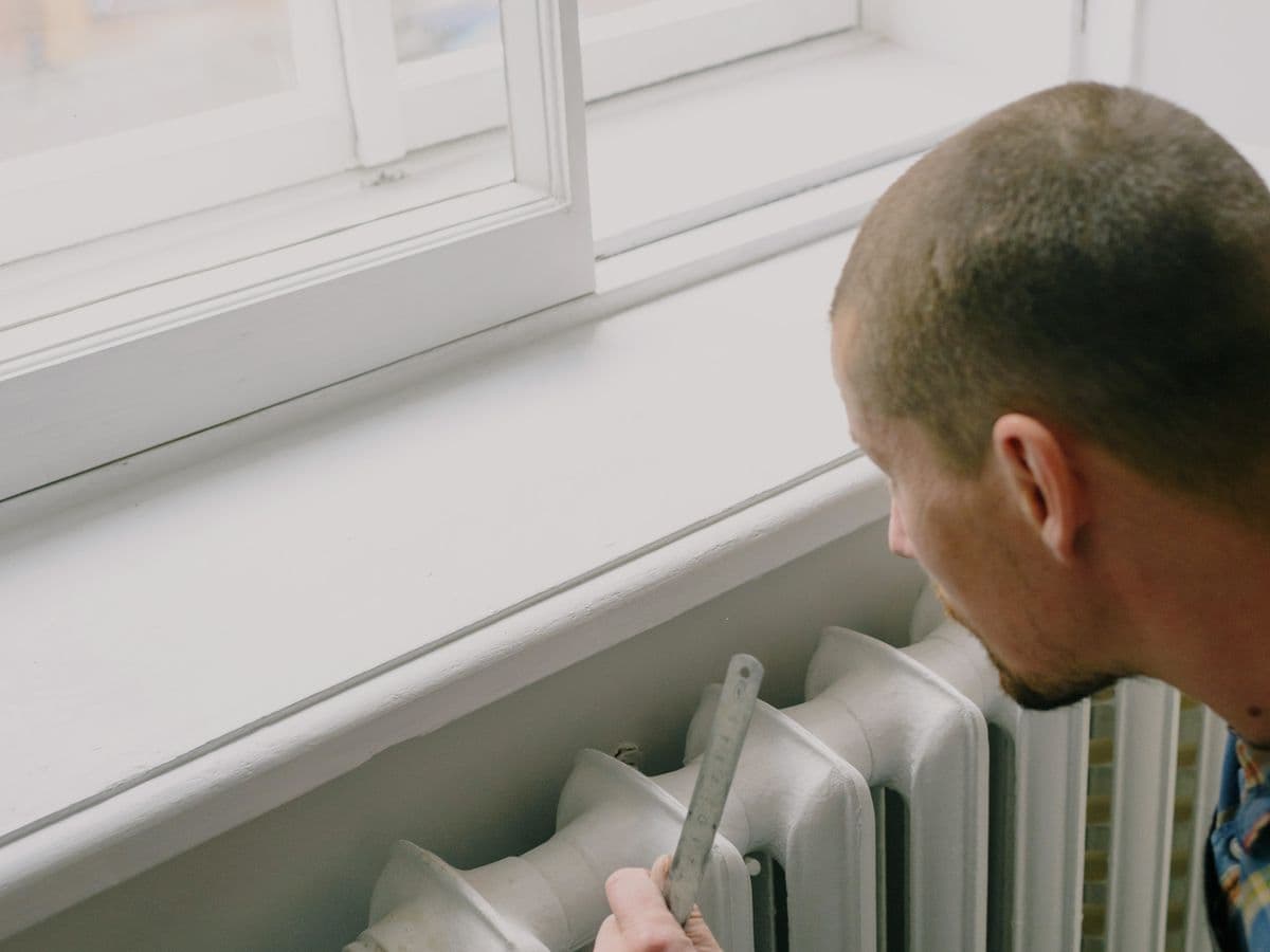 An engineer measuring an existing radiator during a home survey