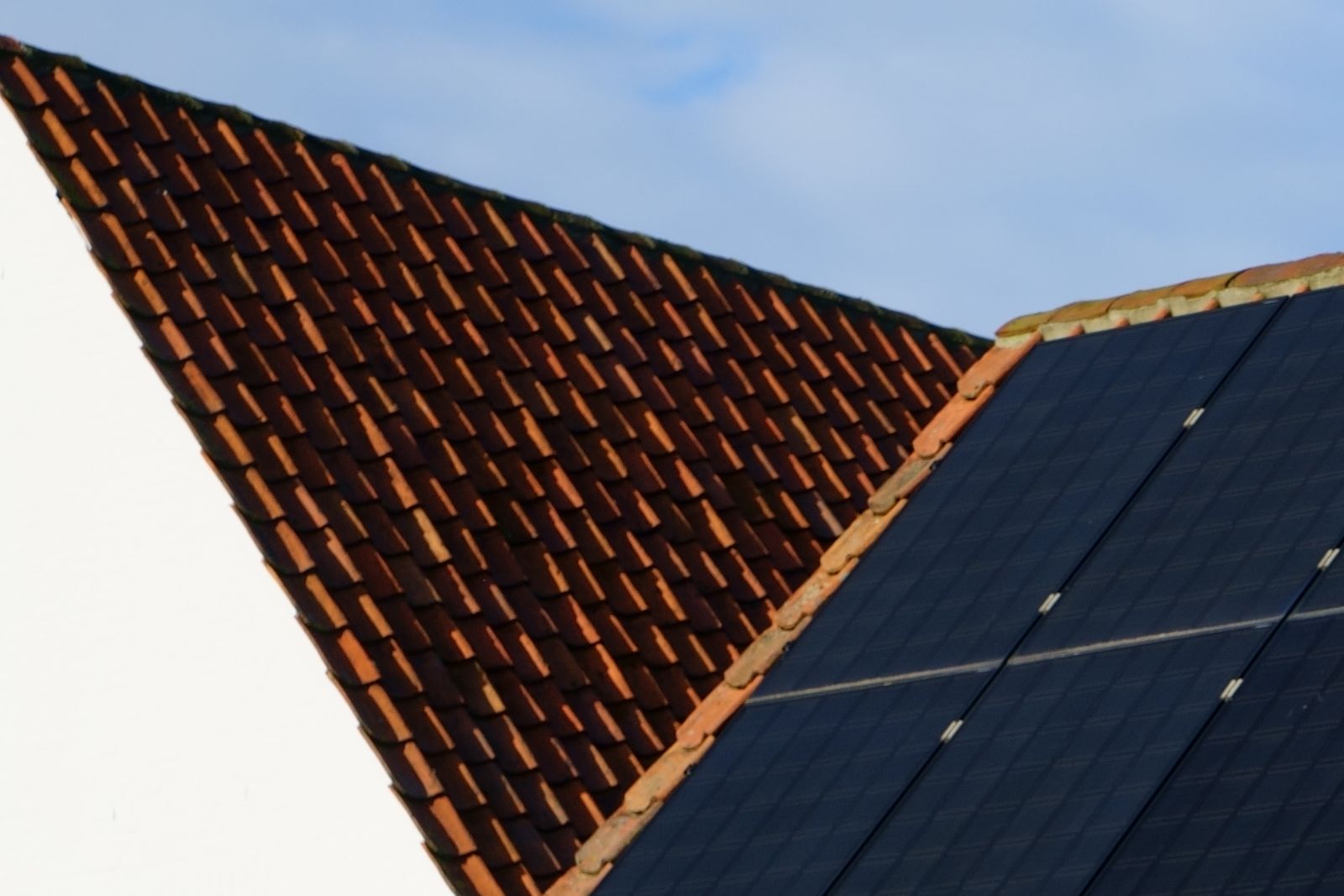 Solar PV panels on a tiled roof against a clear sky